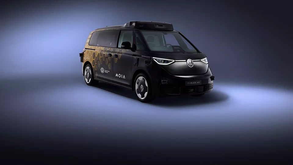 Ein schwarzer Volkswagen Bulli steht in einem dunkel beleuchteten Raum. Das Fahrzeug ist mit futuristischen Designelementen versehen. Auf der Seite steht der Schriftzug "MOIA".