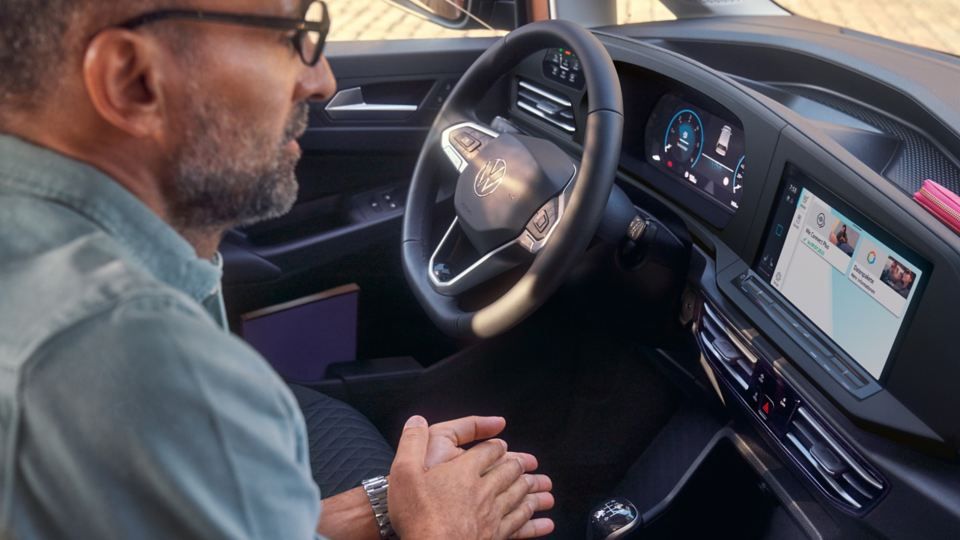 Eine Frau und ein Mann sitzen in einem VW Nutzfahrzeug und beobachtet die Digitalanzeige