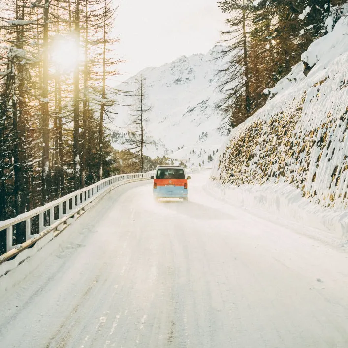 Ein Volkswagen Nutzfahrzeug fährt eine winterliche Straße entlang