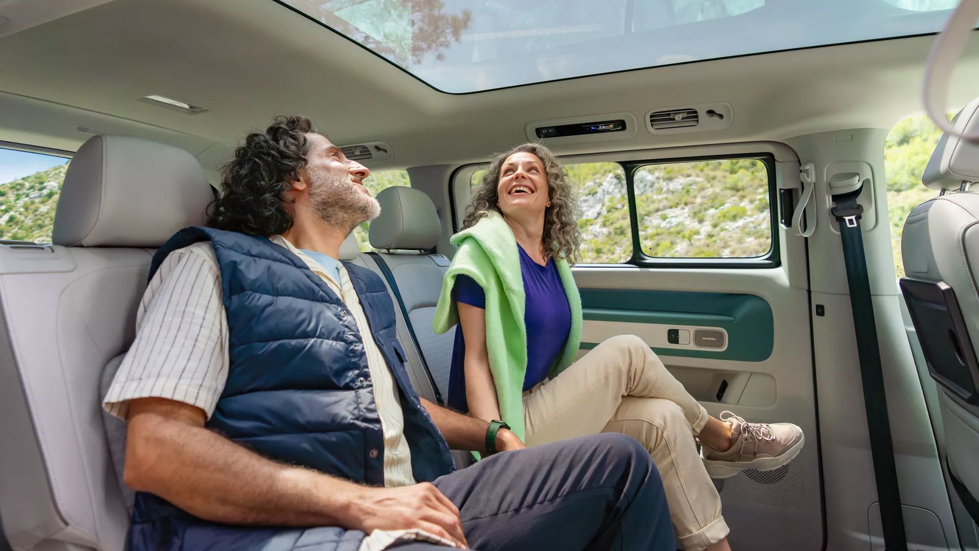 Ein Paar sitzt auf der Rückbank des ID. Buzz Long Wheel Base und schaut durch das Glasdach