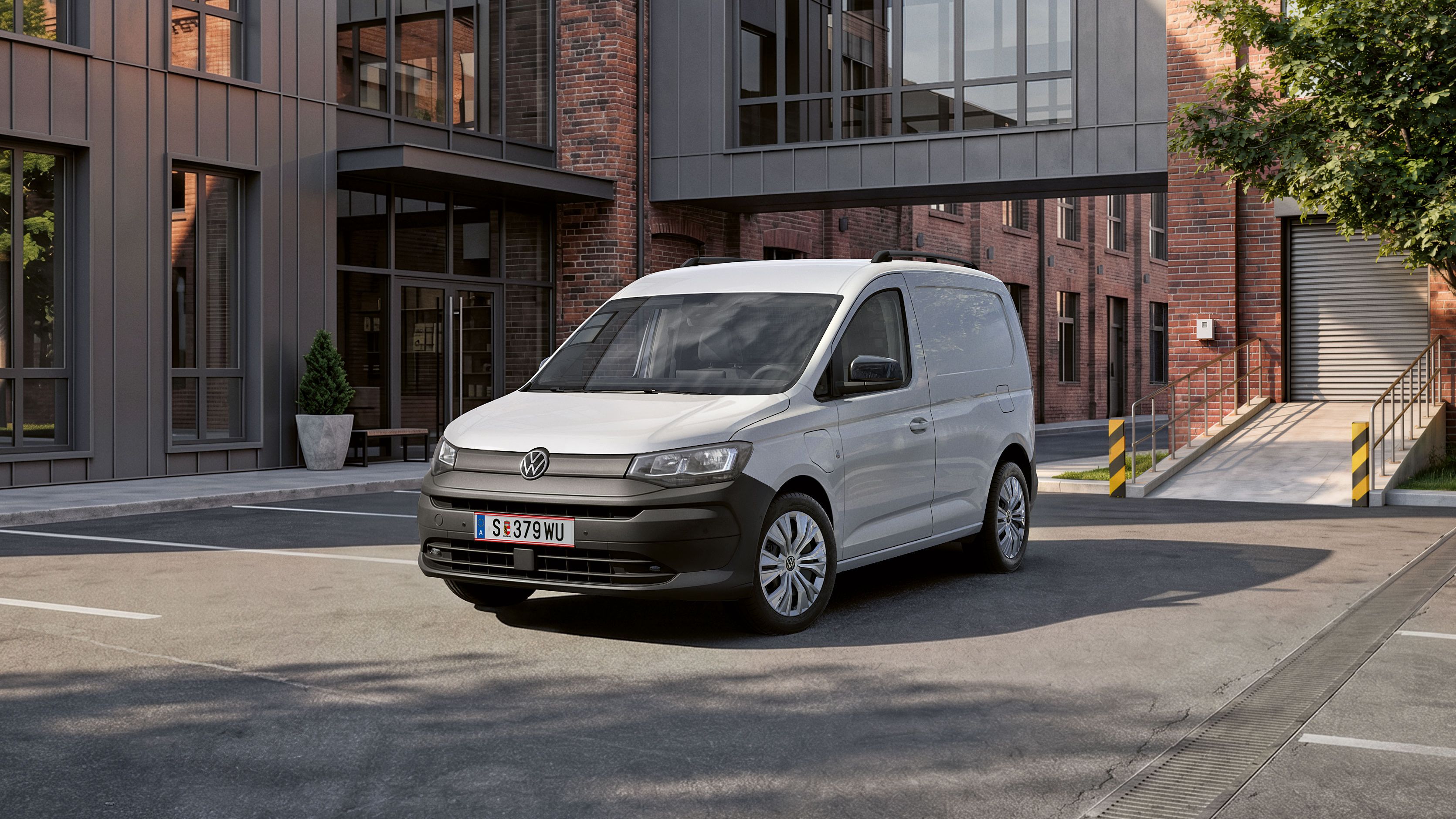 Der neue Caddy Cargo in Weiß steht vor Gebäude.