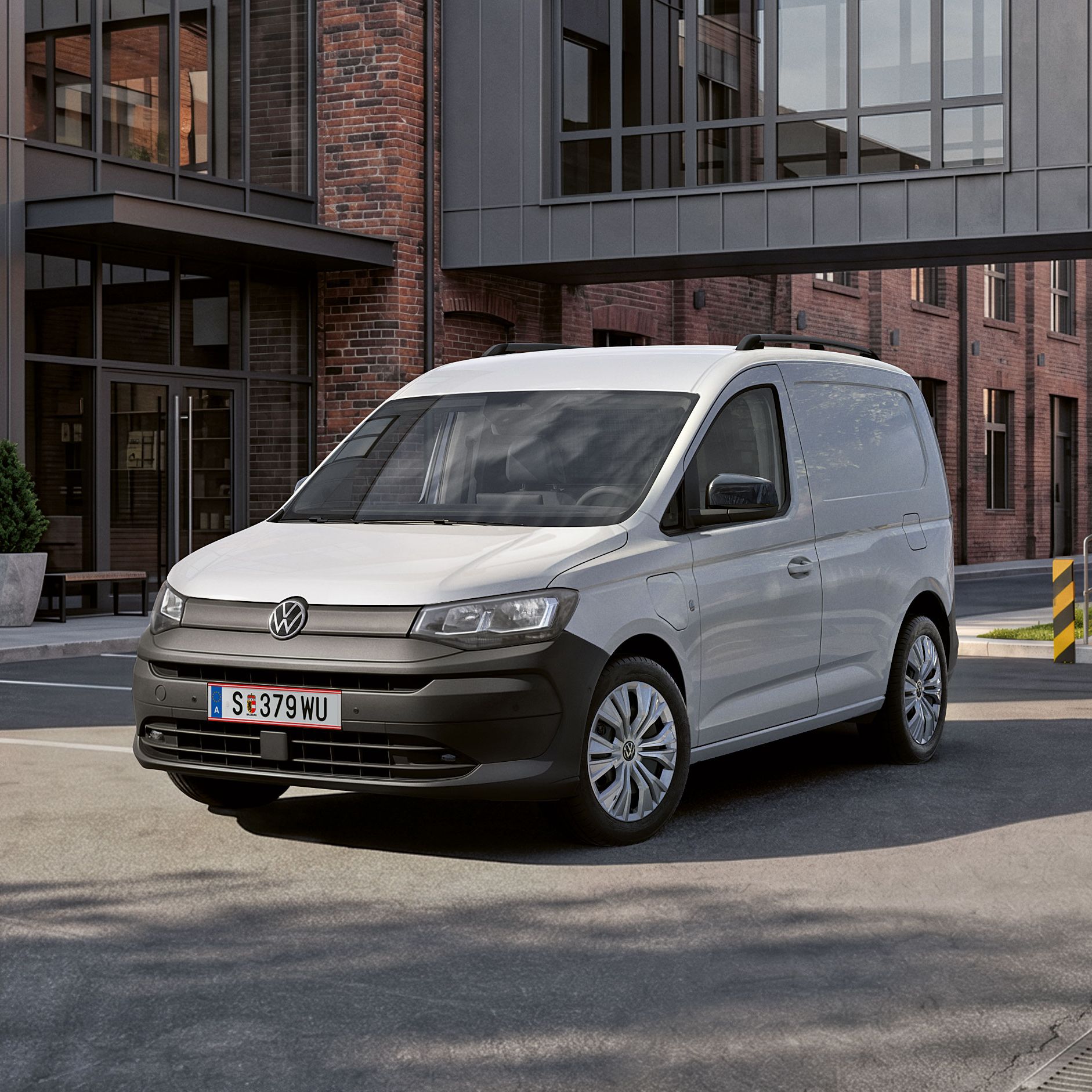 Der neue Caddy Cargo in Weiß steht vor Gebäude.