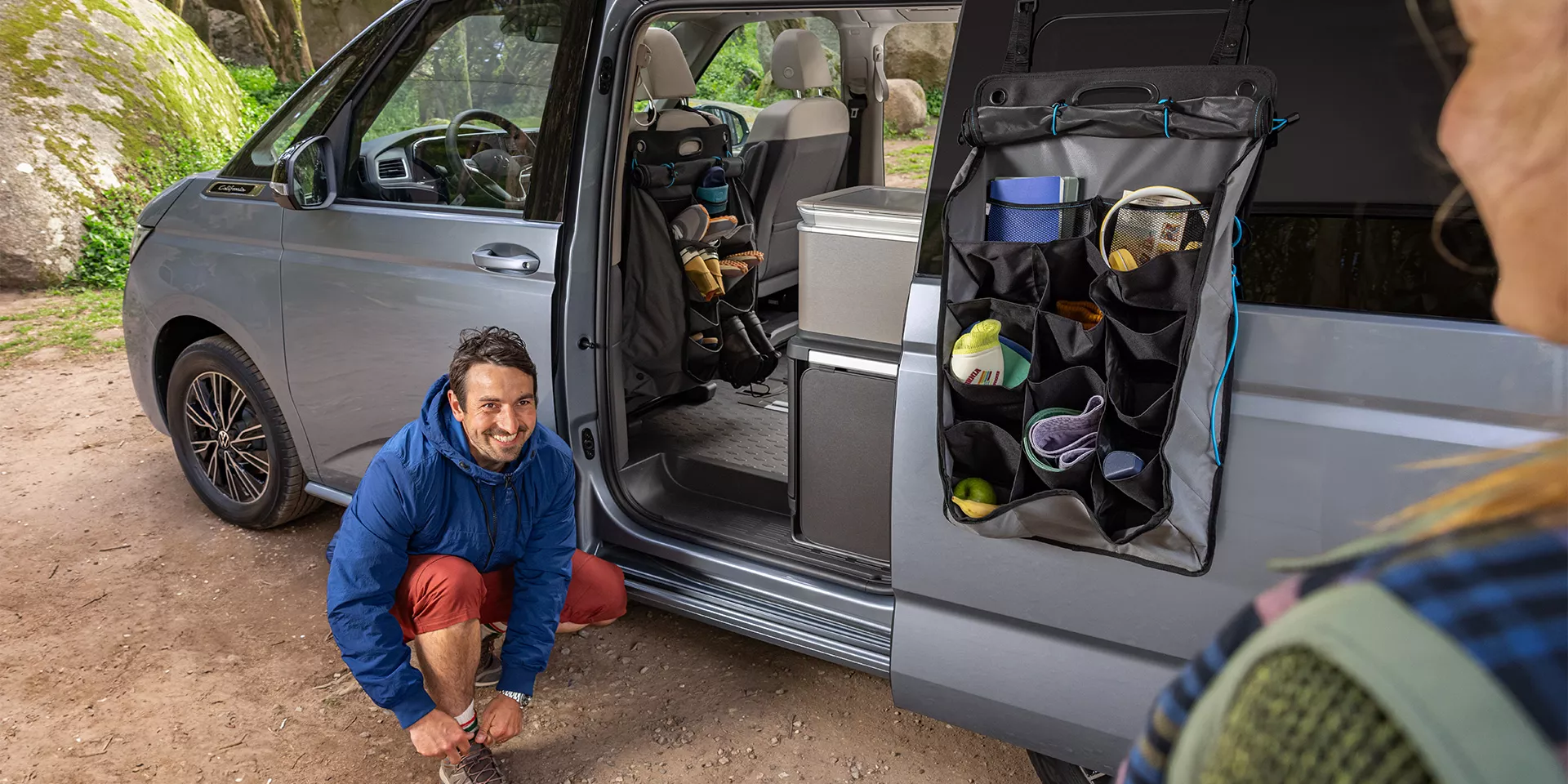 Mann zieht sich Schuhe vor VW California an.