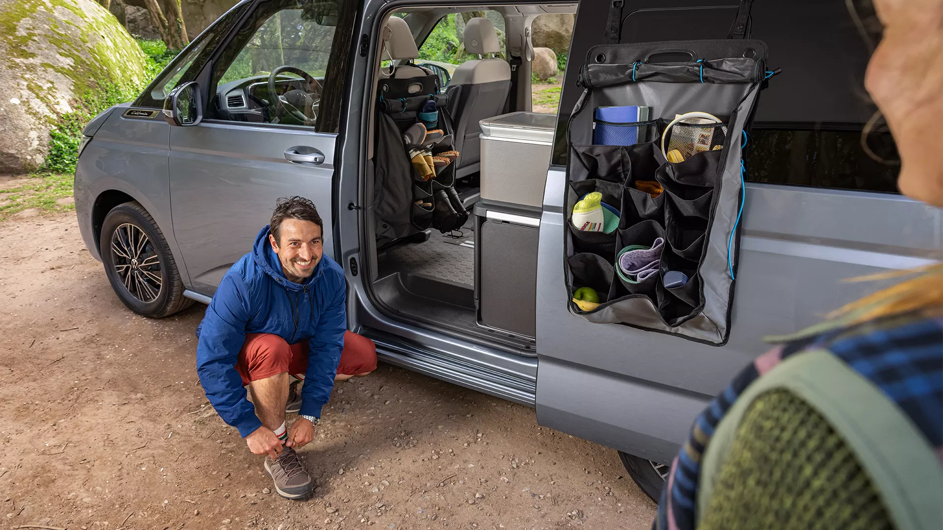Mann zieht sich Schuhe vor VW California an.