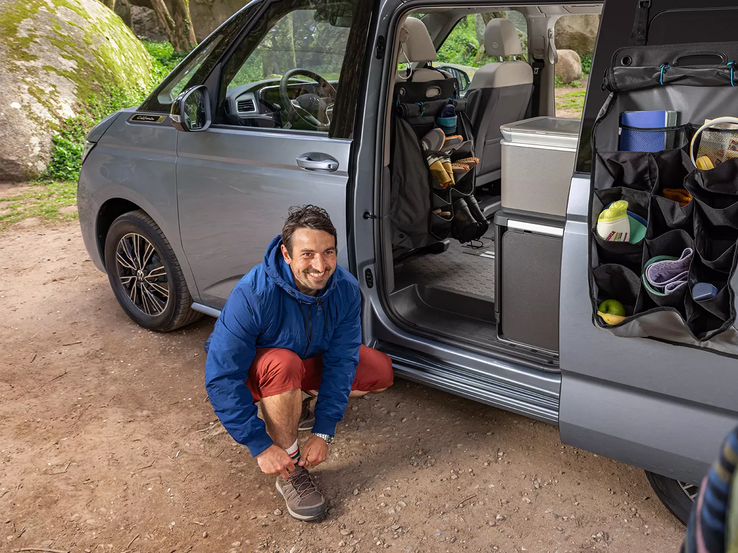 Mann zieht sich Schuhe vor VW California an.