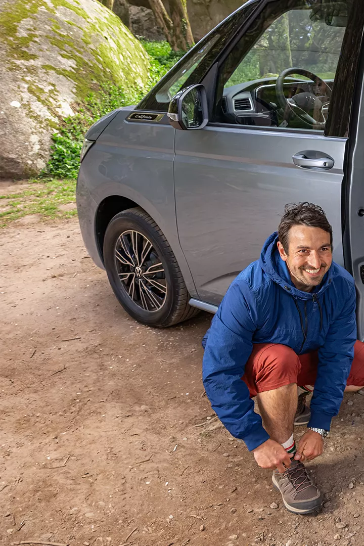 Mann zieht sich Schuhe vor VW California an.
