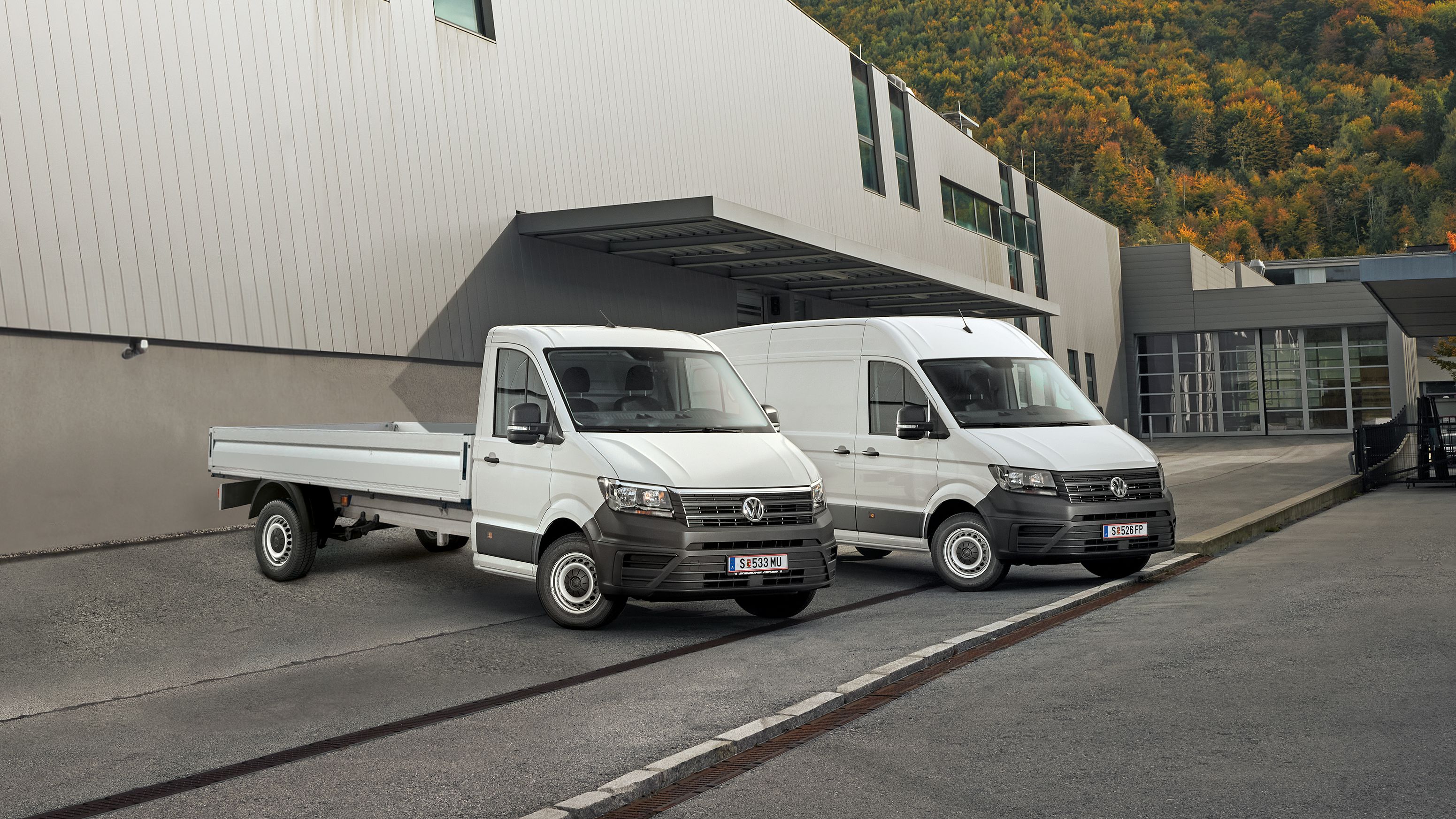 VW Crafter Kastenwagen und Pritschenwagen stehen vor einem modernen Gebäude