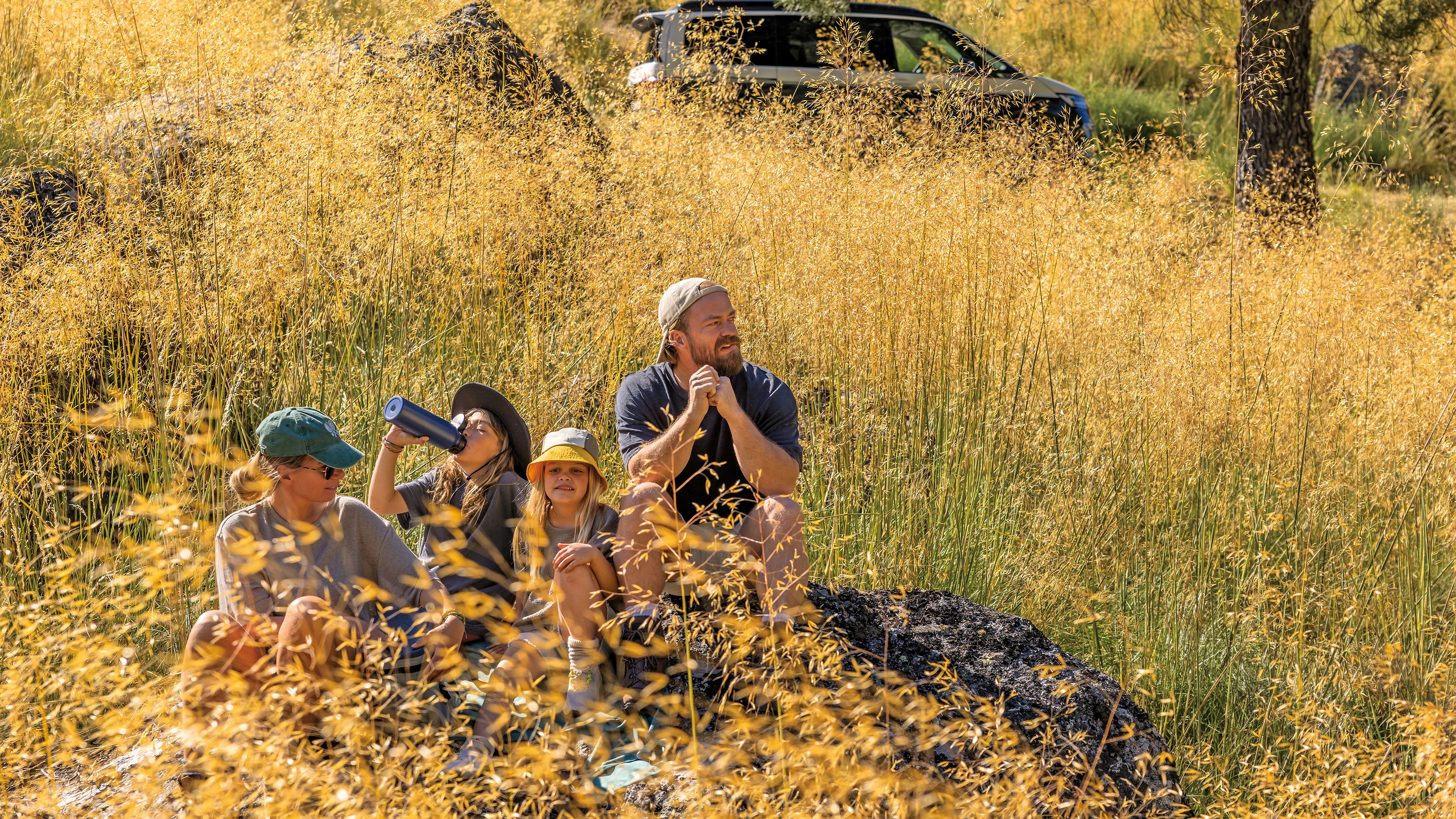 Eine vierköpfige Familie sitzt in der Natur 