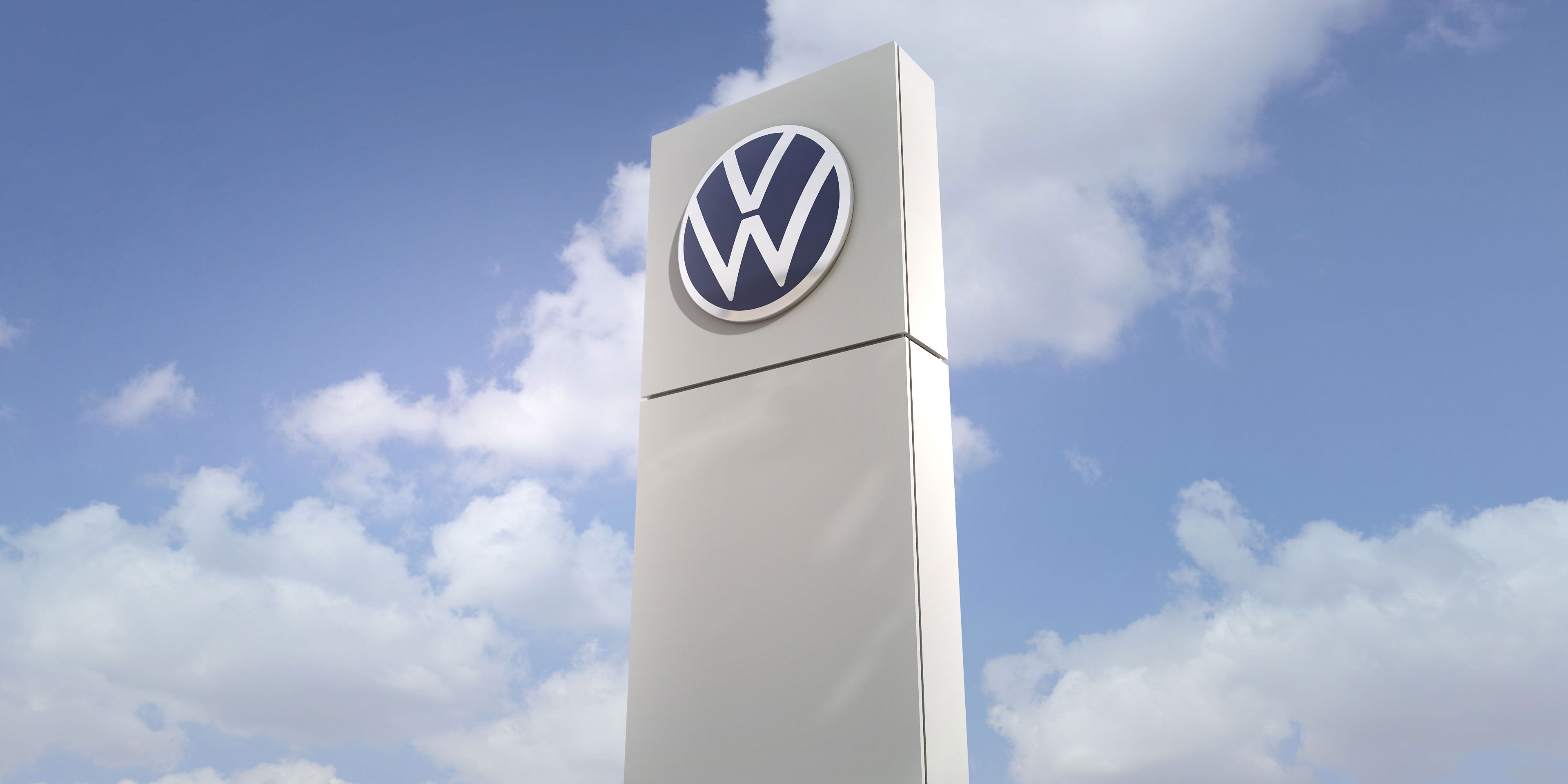 Säule mit Volkswagen Logo mit Himmel im Hintergrund.