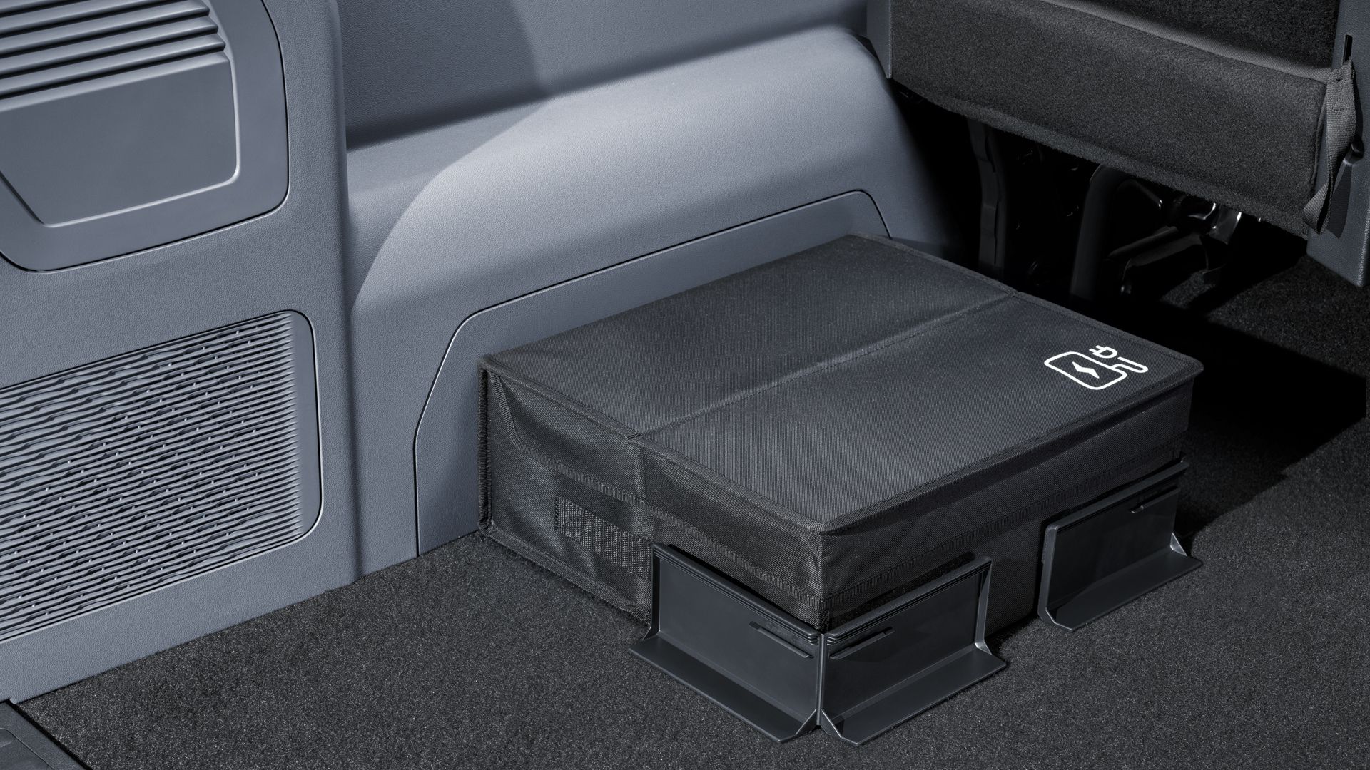 Eine Tasche, die mit Volkswagen Original Cargo Elemente mit Klettsystem am Kofferraumteppich fixiert ist.